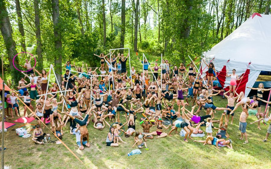 A group of people doing acrobatic poses during the Acronix Festival in 2021, forest trees in the background