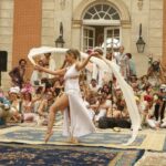 An oriental dancer in front of a group of people celebrating, and taking pictures of her