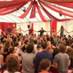A group of people gathering and celebrating under a circus tent