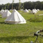 A girl cycling in front of a yurts camping site at the Yoga Mela in Sweden